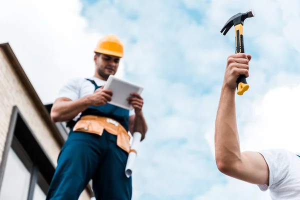 Foco Seletivo Homem Segurando Martelo Perto Colega Trabalho Capacete Usando — Fotografia de Stock