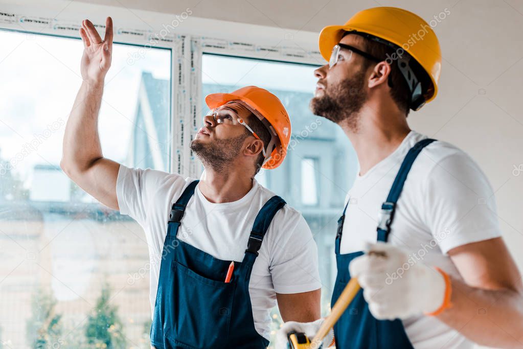 selective focus of repairman gesturing near coworker in house 