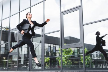 mutlu iş kadını evrak çantası tutarken sokakta levitating