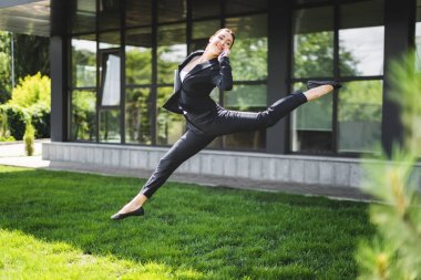 mutlu iş kadını akıllı telefon konuşurken ofis binası yakınında levitating