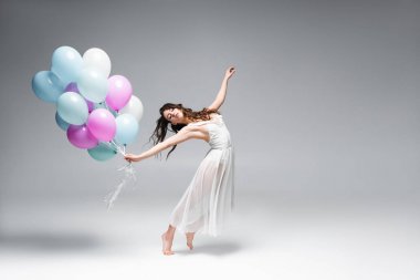 gri arka plan üzerinde şenlikli balonlar ile dans genç, güzel balerin