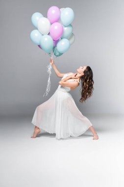 gri arka plan üzerinde şenlikli balonlar ile dans zarif, güzel balerin