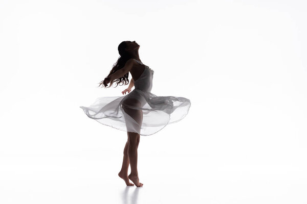Beautiful graceful ballerina in white dress dancing on white background