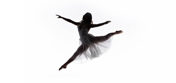 Panoramic shot of young graceful ballerina jumping while dancing isolated on white