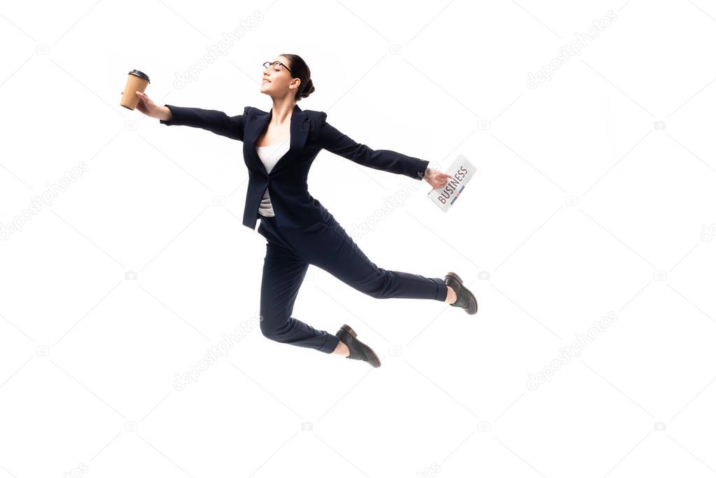 beautiful businesswoman holding newspaper and paper cup while levitating isolated on white