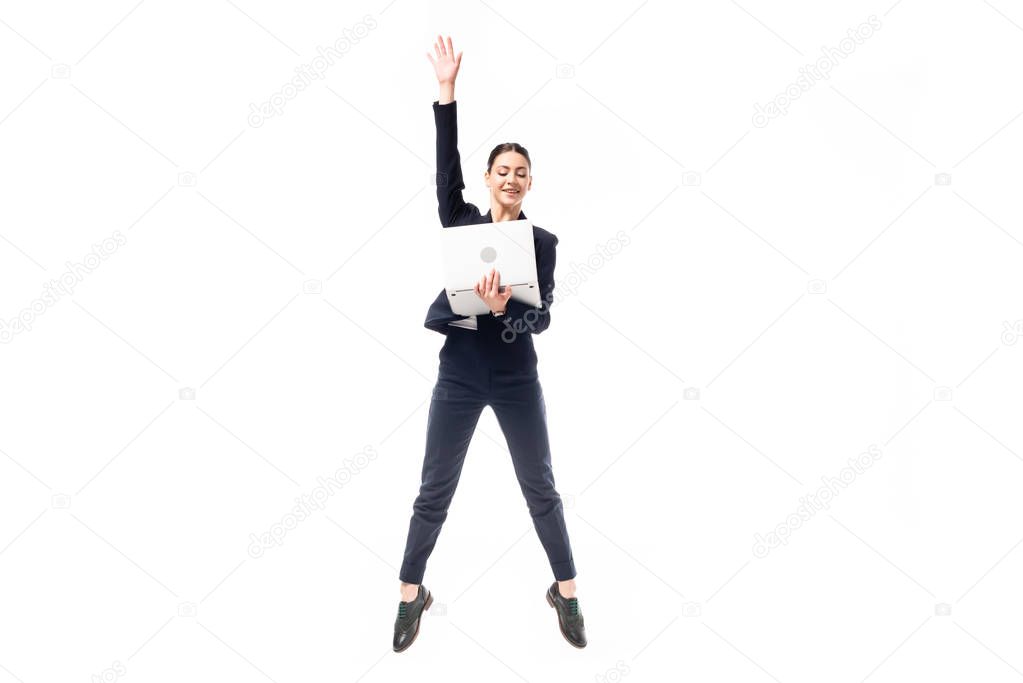 attractive businesswoman jumping while holding laptop isolated on white