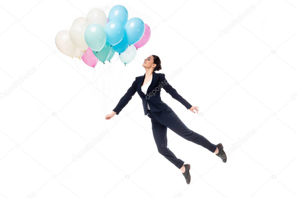 happy businesswoman in formal wear levitating with festive balloons isolated on white