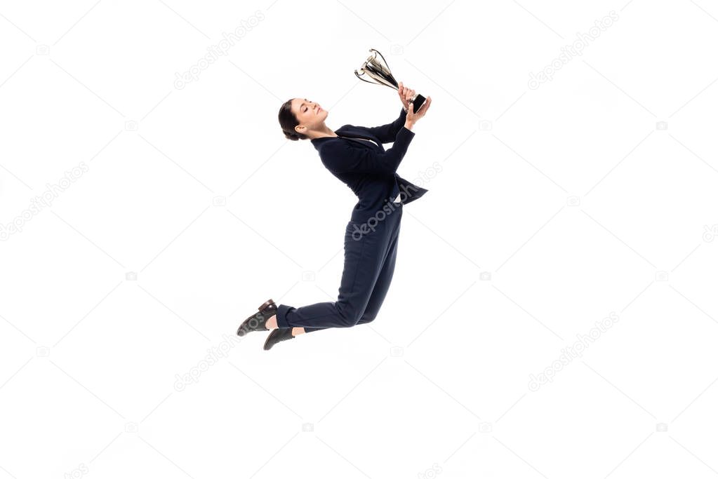 beautiful businesswoman jumping in dance while holding trophy cup isolated on white