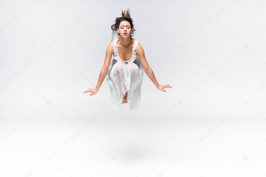 beautiful young ballerina jumping in dance on grey background