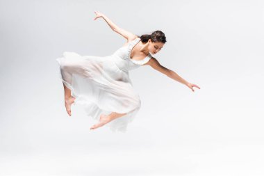 beautiful ballerina in white dress jumping in dance on grey background clipart