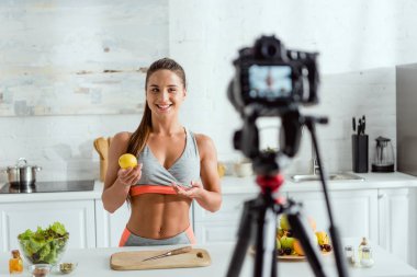 limon tutan ve dijital fotoğraf makinesi bakarak mutlu kız seçici odak 