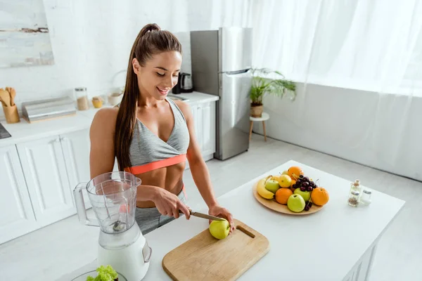 Glückliche Frau Sportkleidung Schneidet Apfel Auf Schneidebrett — Stockfoto