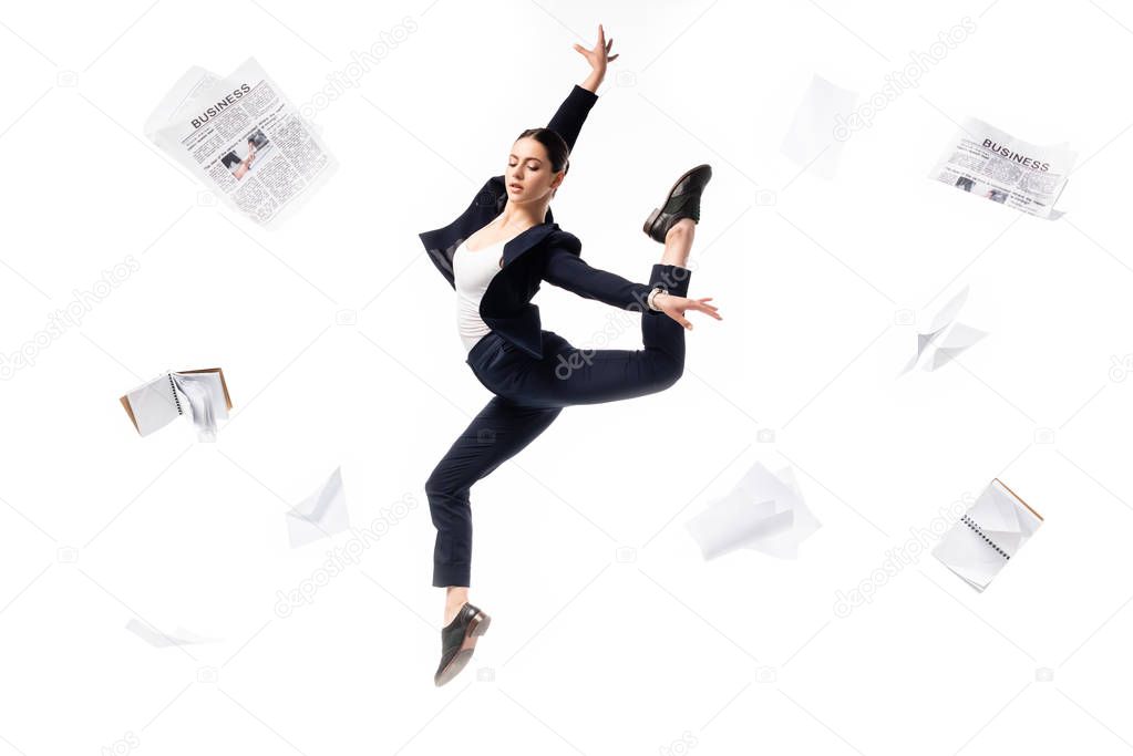 elegant businesswoman dancing surrounded with newspapers, notebooks and papers flying around isolated on white