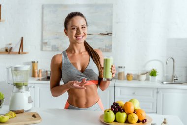 spor gesturing ve lezzetli smoothie ile cam tutan neşeli kız seçici odak 
