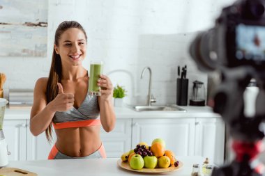 smoothie ile cam tutan ve başparmak gösteren mutlu kız seçici odak 