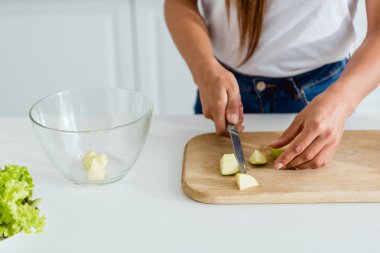 cropped view of young woman cutting green apple on chopping board  clipart