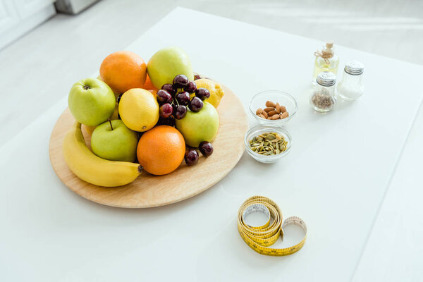 selective focus of tasty and ripe fruits on plate near measuring tape on table 