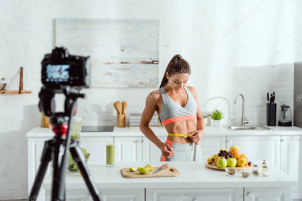 Selective focus of girl measuring waist near fruits and