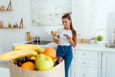 akıllı telefon kullanarak ve kredi kartı tutarak mutlu kız seçici odak