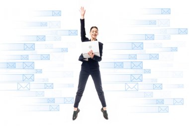 smiling businesswoman using laptop while jumping on background with e-mail icons isolated on white clipart
