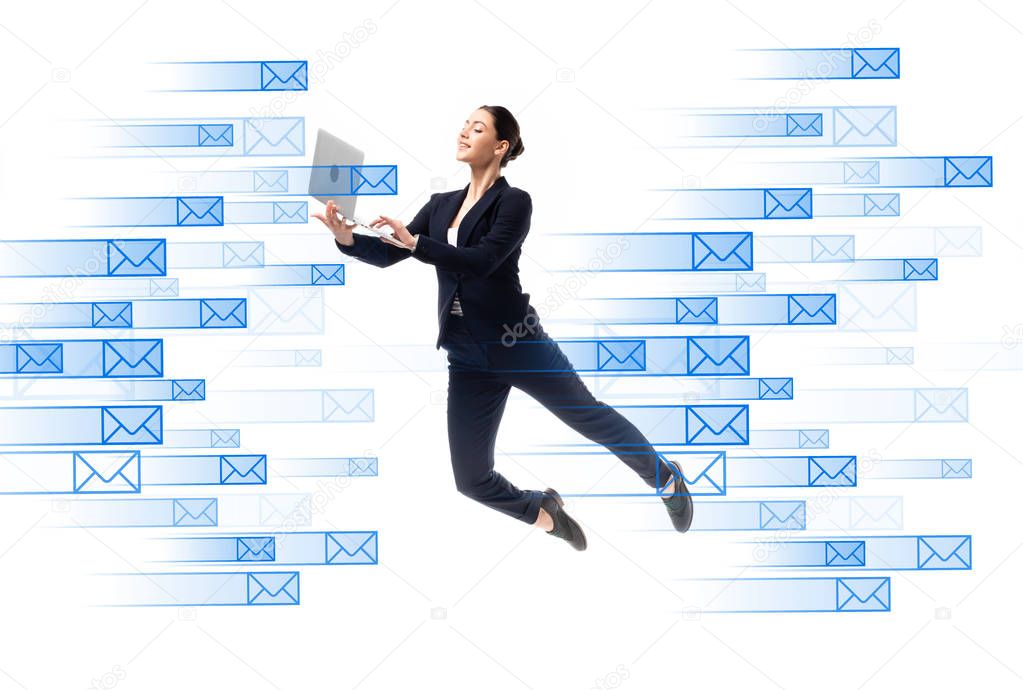 Young businesswoman using laptop while levitating near e-mail icons isolated on white