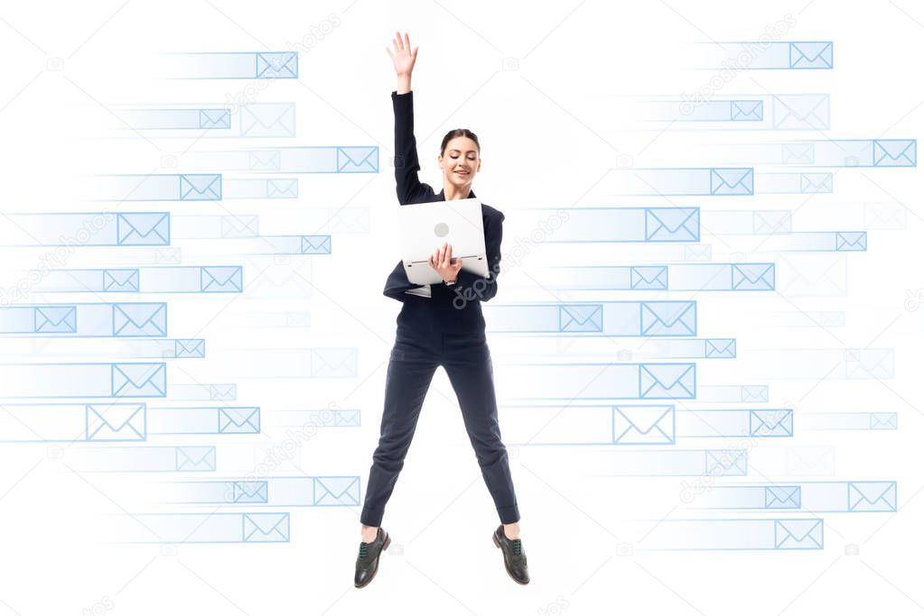 Smiling businesswoman using laptop while jumping on background with e-mail icons isolated on white