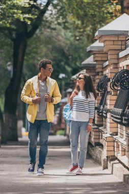 Sırt çantası ile kadının yanında yürüyen güneş gözlüğü iki ırklı adam