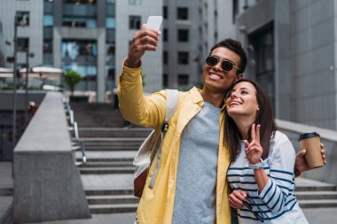 Akıllı telefonda selfie çeken kadınla güneş gözlüğü takan iki ırklı adam