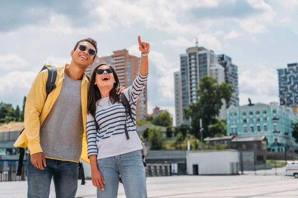 Mujer Señalando Con Dedo Sonriendo Cerca Racial Amigo Con Mochila — Foto de Stock