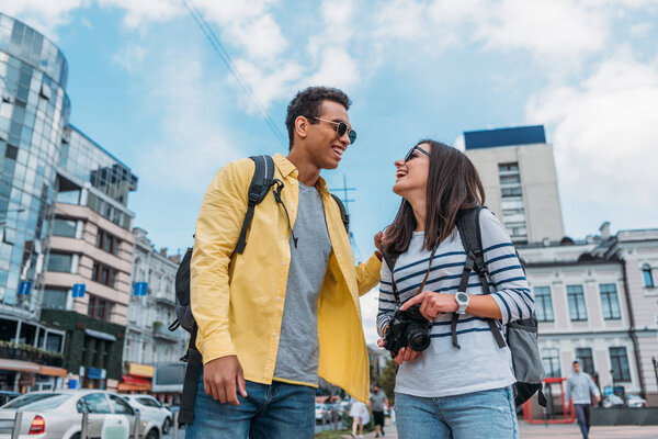 Mixed race man and woman with digital camera looking at each other
