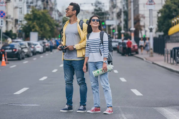 Mulher Segurando Mapa Estrada Perto Amigo Racial Com Mochila Câmera — Fotografia de Stock