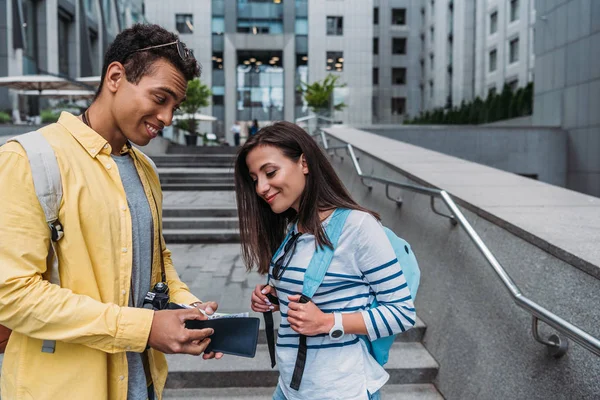 Mujer Con Mochila Cerca Amigo Racial Mirando Cartera Calle —  Fotos de Stock