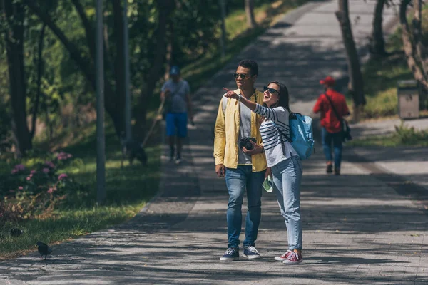 Menina Feliz Apontando Com Dedo Perto Homem Raça Mista Parque — Fotografia de Stock