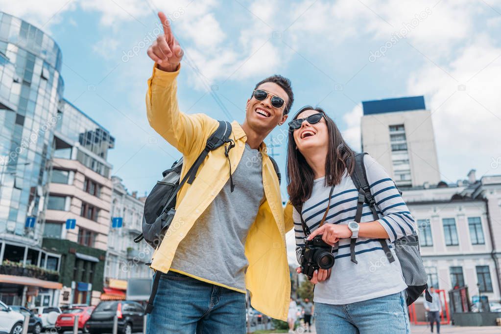 Mixed race man pointing with finger and woman with digital camera and backpack