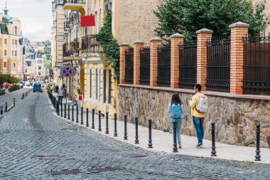 back view of girl and mixed race man walking in city  clipart