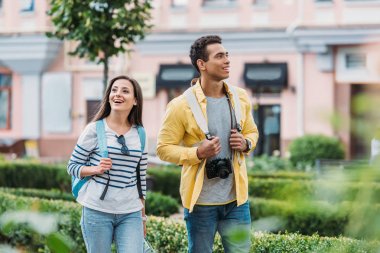 neşeli iki ırklı erkek ile yürüyen mutlu kadının seçici odak 