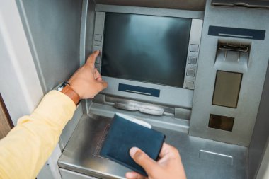 karışık ırk adam atm makine üzerinde düğmeye basarak ve cüzdan tutan kırpılmış görünümü 