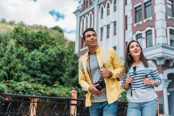 Chica Feliz Tocando Mochila Mientras Está Pie Con Hombre Raza — Foto de Stock