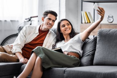 mutlu çok kültürlü öğrenciler gülümseyerek ve dairede selfie alarak 