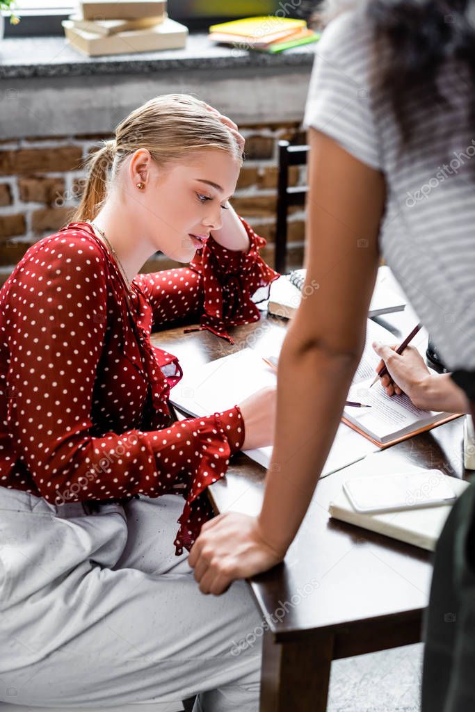 selective focus of student in red blouse looking at notebook