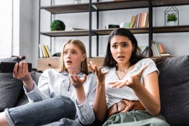 uzaktan kumanda tutan ve dairede uzağa bakan çok kültürlü arkadaşlar 