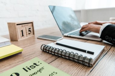 dizüstü bilgisayar ve ahşap küpler yakınında dizüstü bilgisayarda yazma kadın seçici odak 
