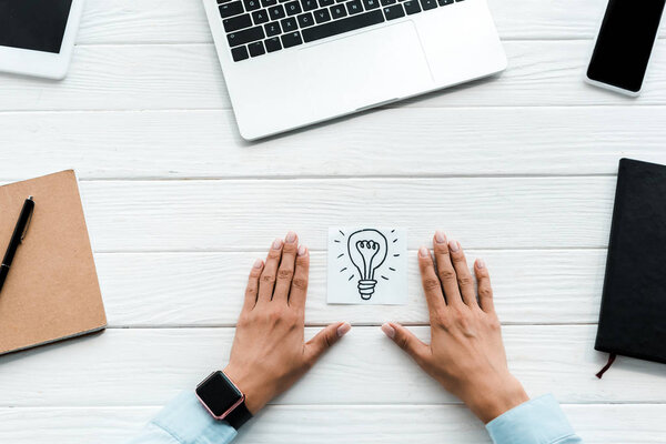 вид сверху женщины рядом с картой с нарисованной лампочкой и гаджетами
