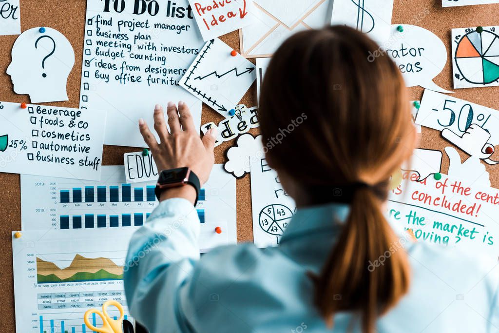 back view of woman standing near notice board with letters in office 
