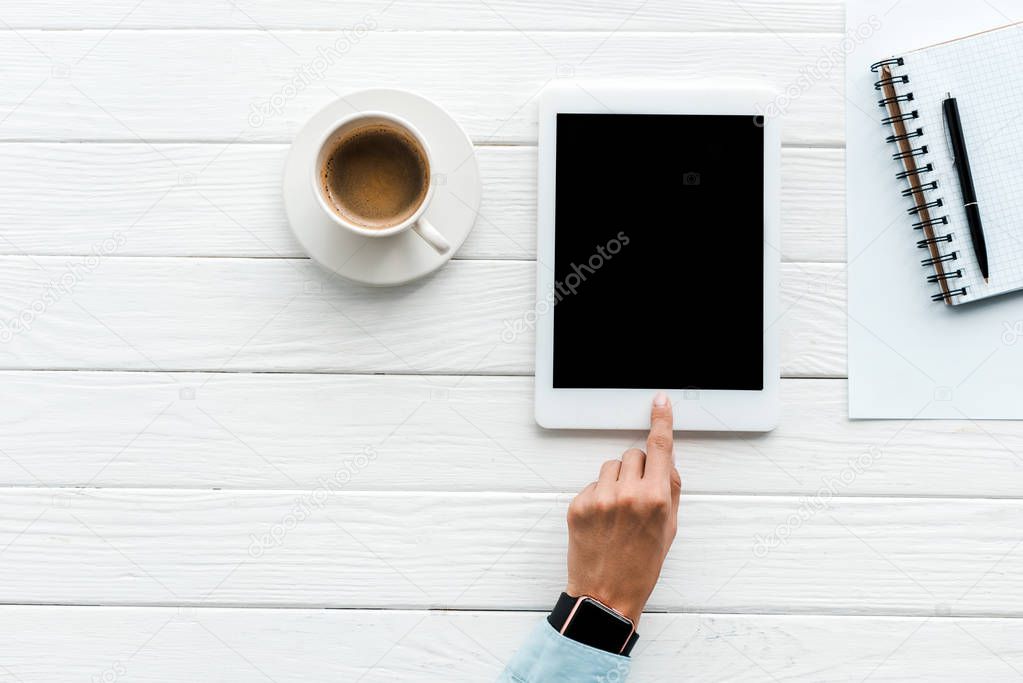 top view of woman pointing with finger at digital tablet with blank screen near cup of coffee 