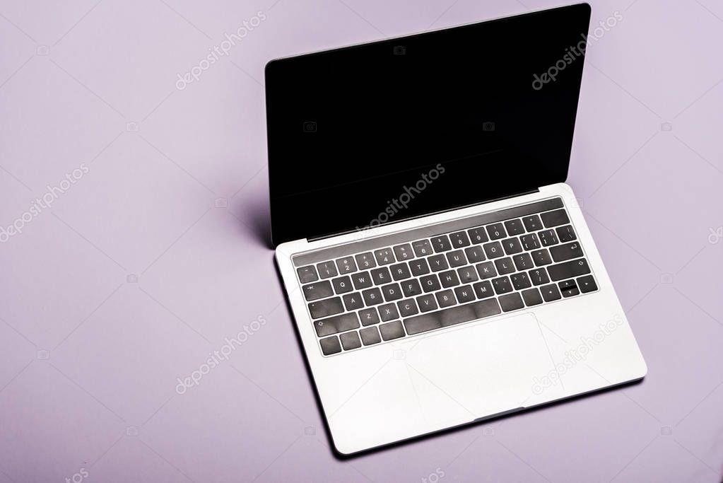 overhead view of modern laptop with blank screen on purple 