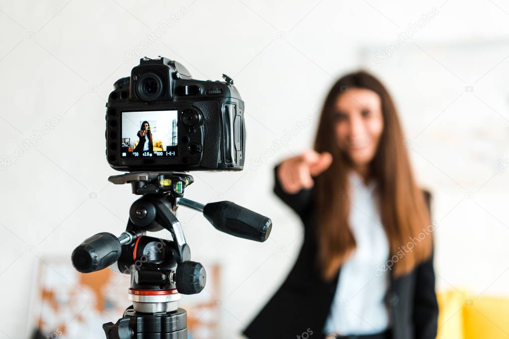 selective focus of digital camera with happy video blogger gesturing on screen 