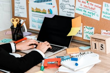 cropped view of woman using laptop with blank screen near lettering on notice board clipart