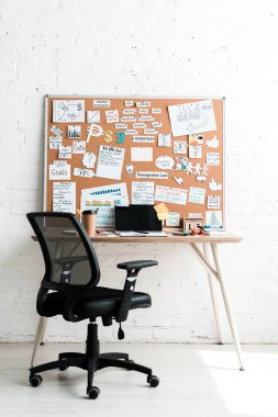 notice board with lettering on sticky notes near table and chair  clipart