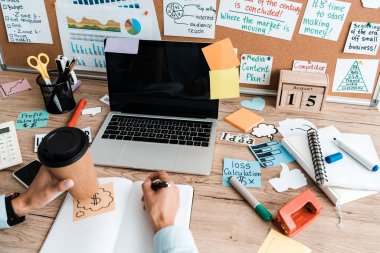 cropped view of businesswoman with pen and disposable cup near laptop with blank screen  clipart